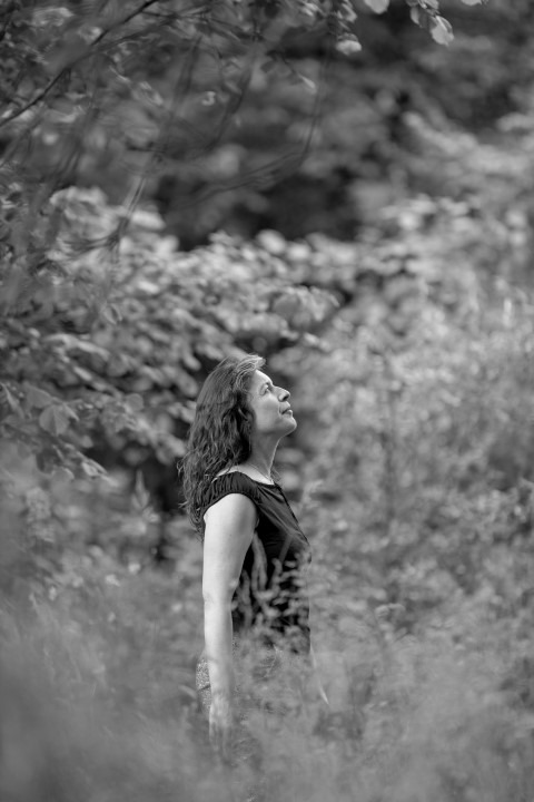 photo noire et blanc de sandra marchand debout dans la nature de profil tête levée