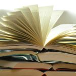 image de livres ouverts empilés sur une table dont le dernier livre est ouvert pour représenter les livres et la lecture