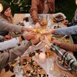 image prise au-dessus d'une table où 7 personnes sont en train de trinquer au milieu d'un repas pour représenter la convivialité